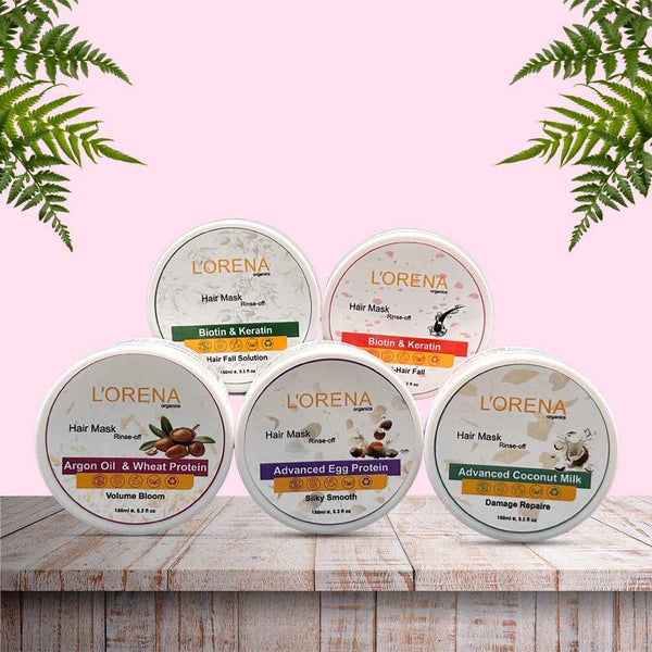 Lorena hair mask containers on a wooden surface with a pink background and green leaves.