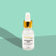 Skincare serum bottle with dropper on a green background